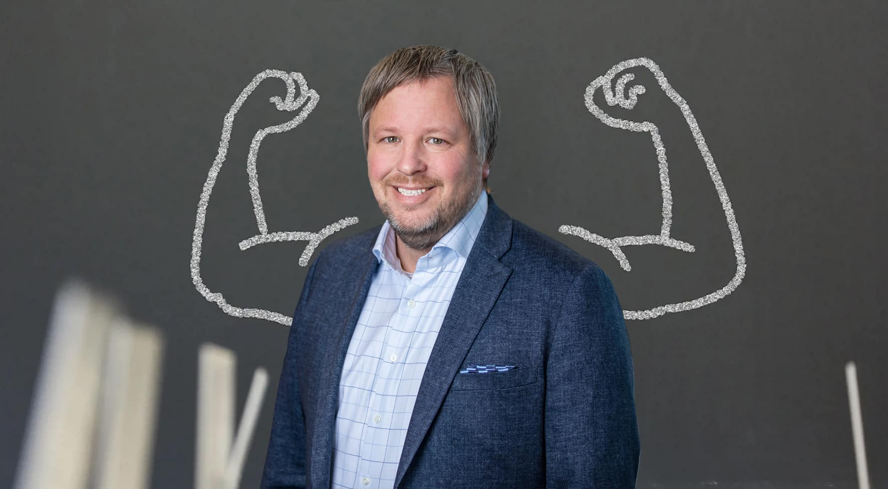 Henrik Palmblad Wennergren står framför en vägg med två starka armar.