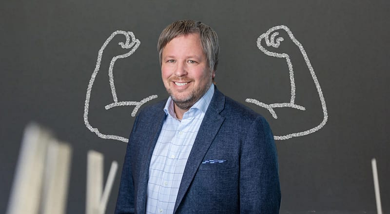 Henrik Palmblad Wennergren står framför en vägg med två starka armar.